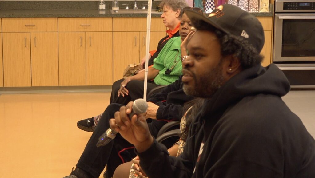 Chris Goode, a cast member from the play. A black male with curly hair, baseball cap and close cropped beard.